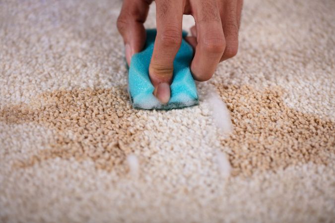 Hand using cloth to remove stain from carpet during stain removal service in Sydney